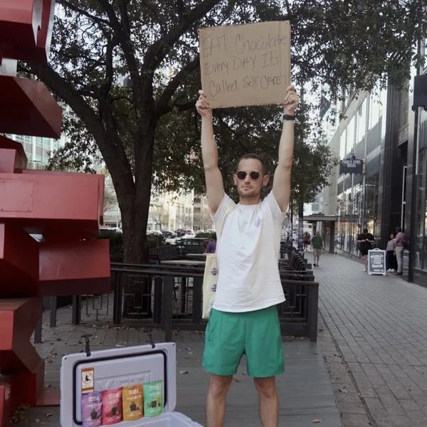 David at SXSW holding an Eat Chocolate Every Day sign beside a cooler of Nebula pouches