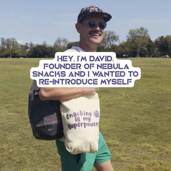 David in a park holding a Snacking is my superpower tote